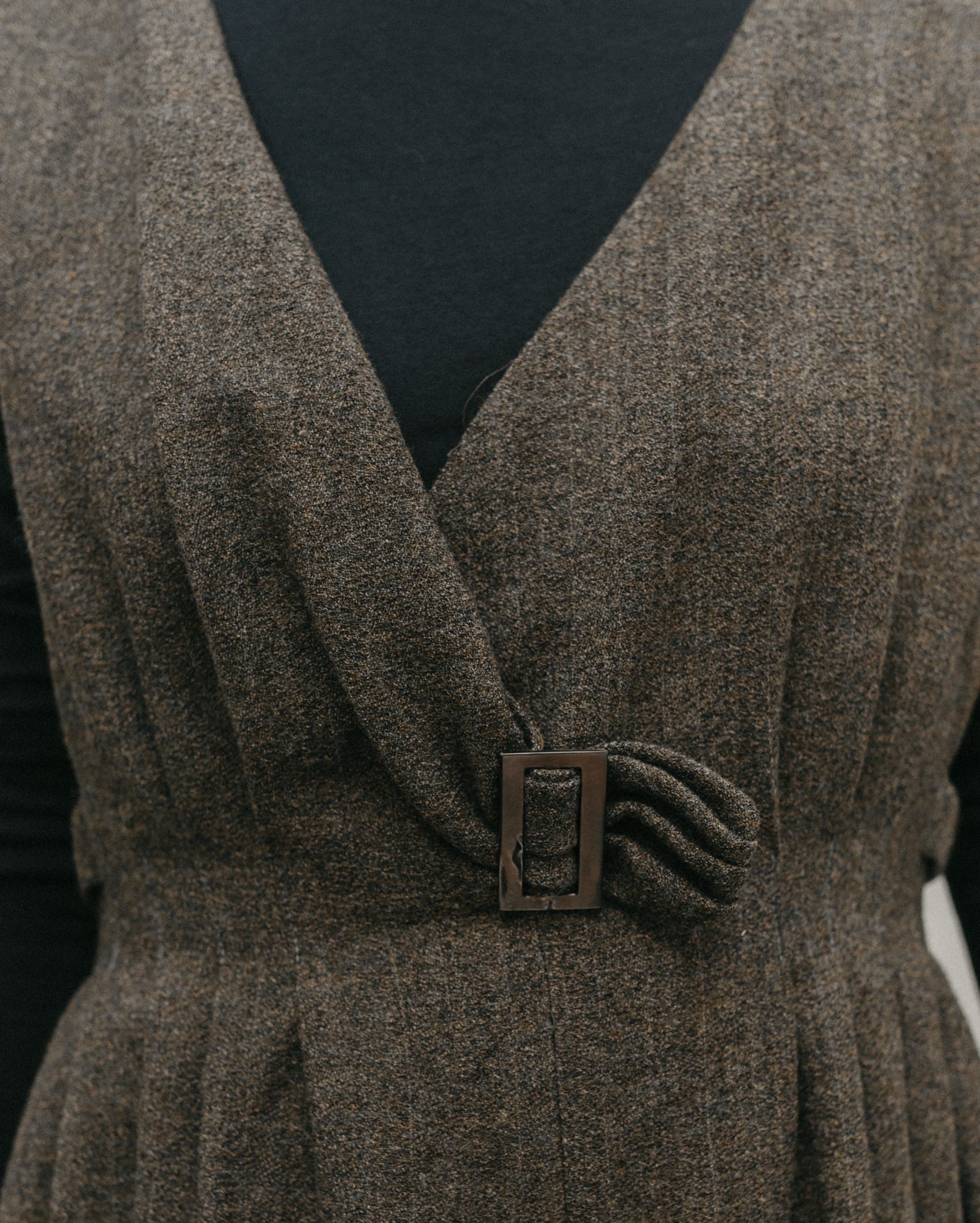 close up of the front of the jumper, plunging V-neck with pleats . Fitted waist trimmed with a purchase buckle