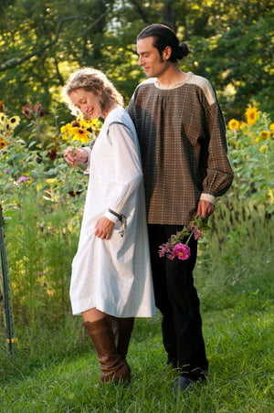 Young white man and woman standing surrounded by greenery, standing in front of sunflower wearing 148 Black Forest Smock