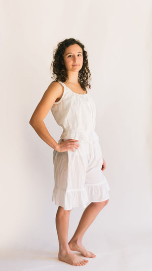 Photo of young woman wearing camisole and drawers. standing slightly sideways with hand on her hip.