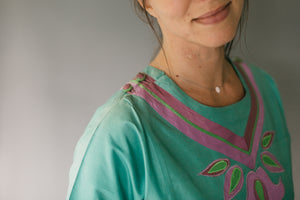 Close up photo of neckline and shoulder. Shows buttons at side of shoulder and neck opening.