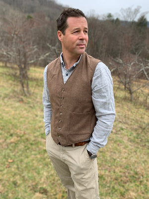 Man standing in a field turned slightly to the left looking right, wearing View A of 222 Vintage Vests collarless but with two pockets.