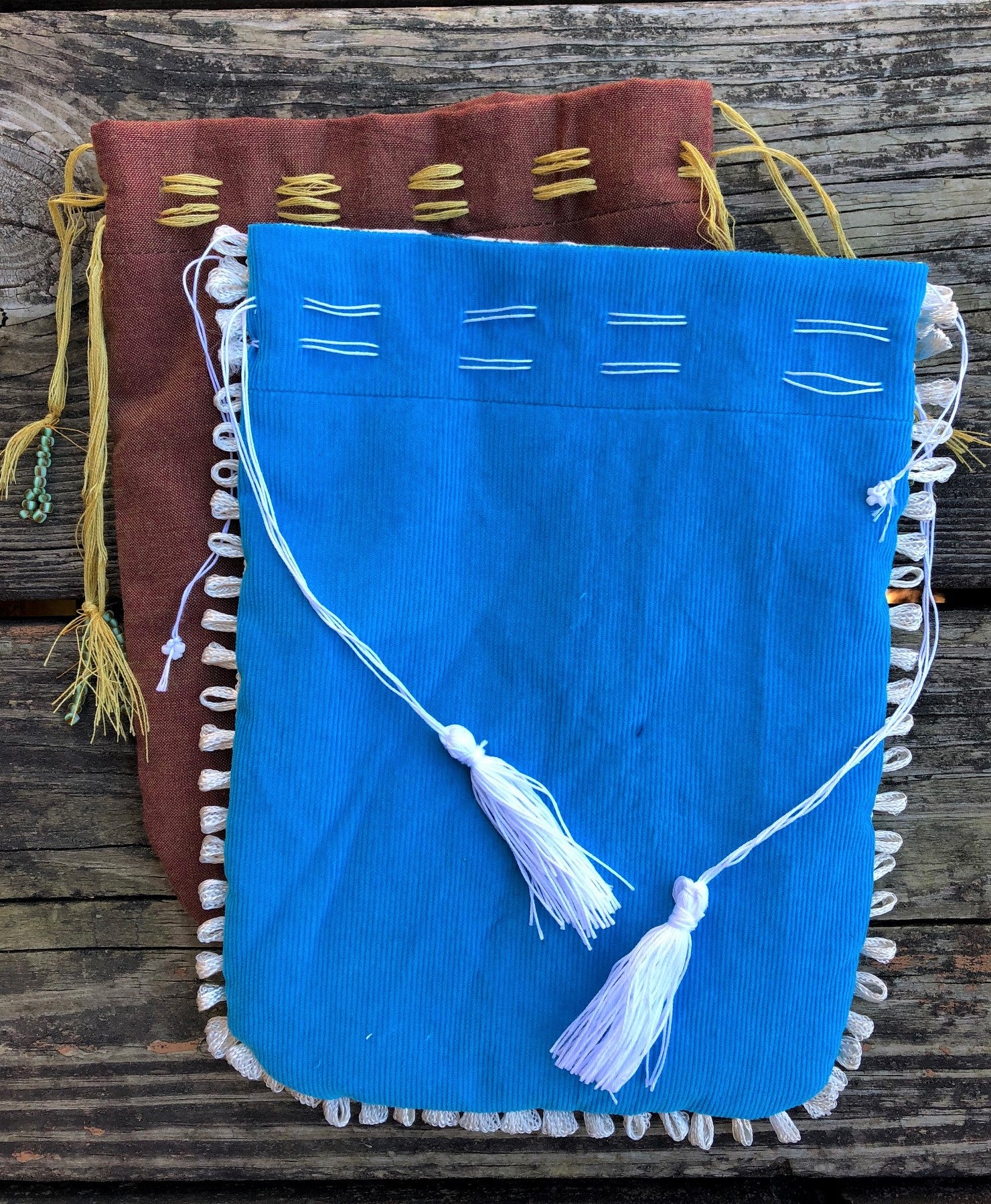 Two Turkish Pouches - 1 brown with yellow cording; 1 blue with white draw strings and tassels and white trim.