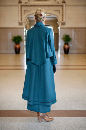 Back view of Young blonde woman standing in a lobby wearing the Metropolitan Suit.