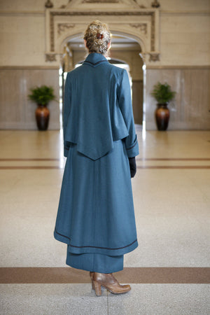 Back view of Young blonde woman standing in a lobby wearing the Metropolitan Suit.
