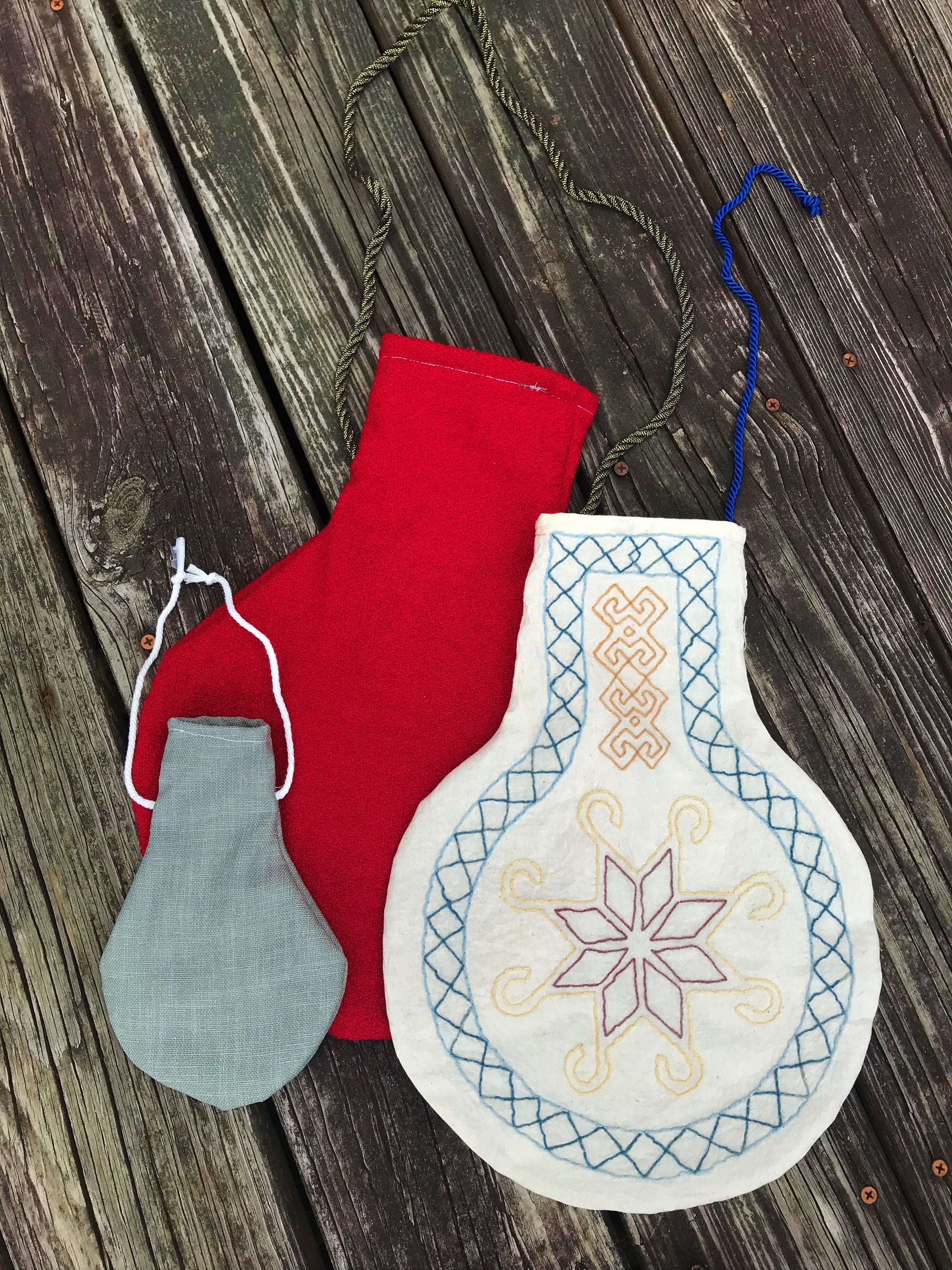 Blue Japanese Carpenters bag hanging on a wooden wall. Embroidered with white sashiko and holding rolls of paper.