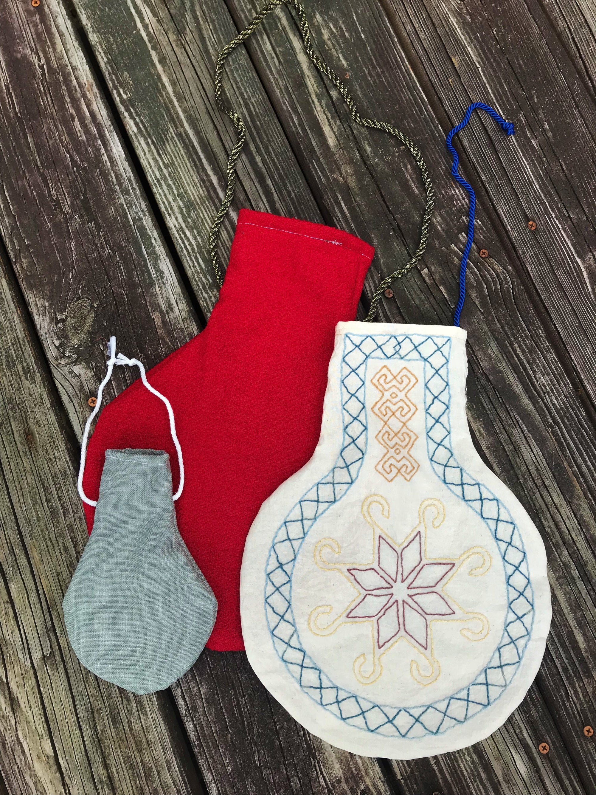 Three Uzbek pouches - 1 small grey with white drawstring; 1 large red with gold drawstring, and one large cream colored with red, blue, and yellow embroidery.