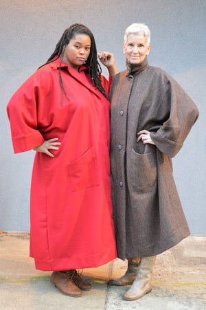 An African American woman on the left, and a Caucasian woman on the right. Both are wearing the Basics Overcoat. One in Scarlett Red and the other is a wool chocolate brown.